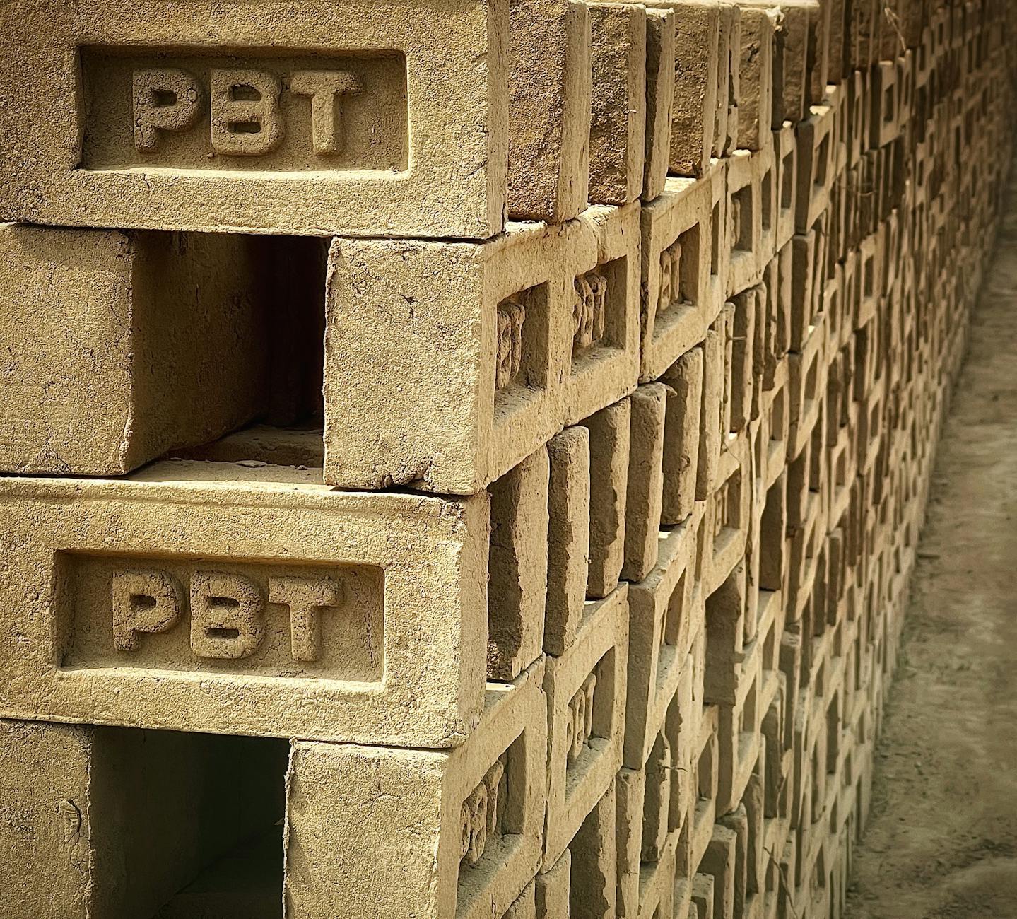 Zbliżenie na stos betonowych pustaków z oznaczeniami PBT