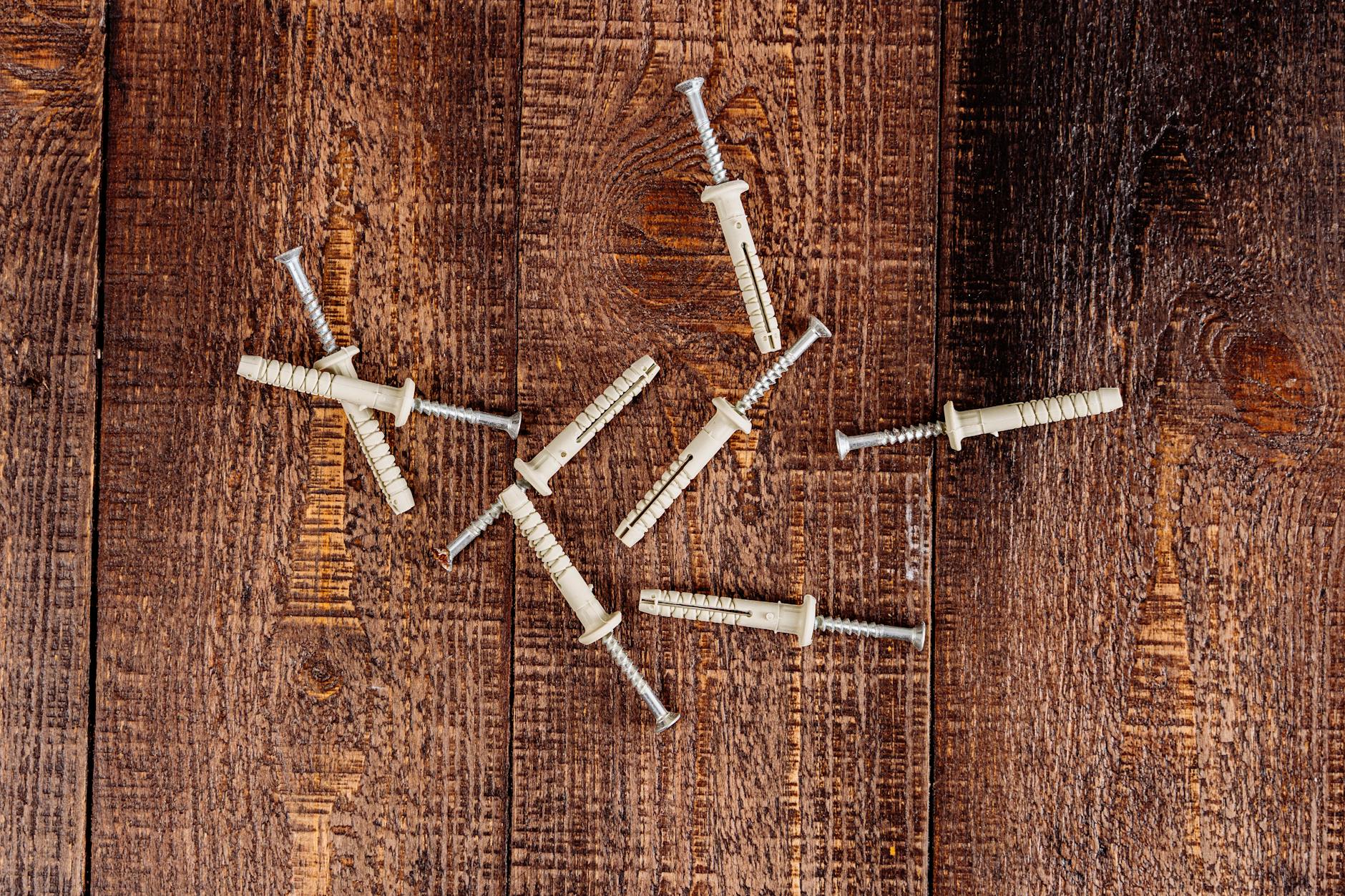 Deski z drewna konstrukcyjnego z rozsypanymi wkrętami z bliska