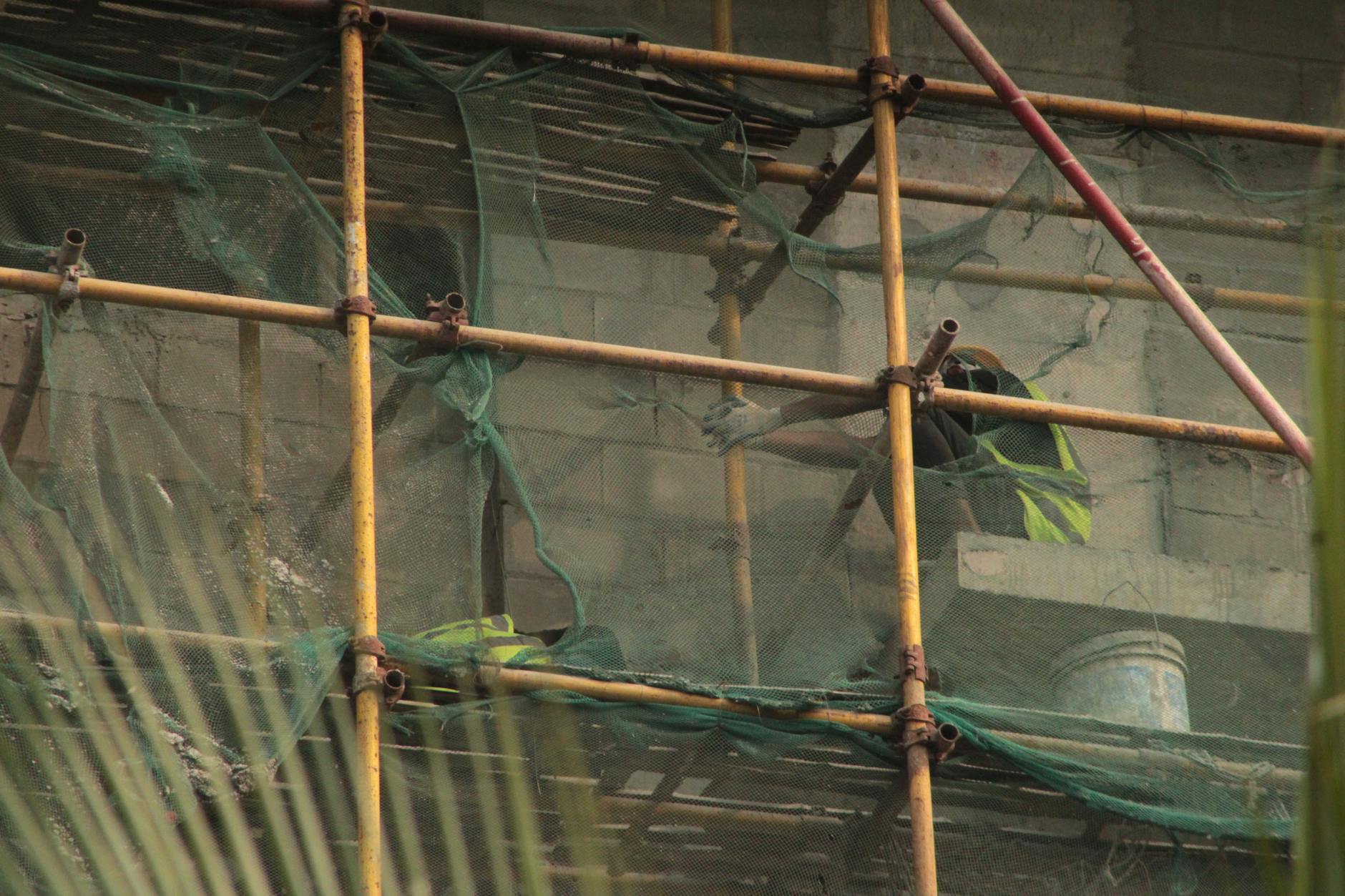 Pracownicy ocieplający elewację budynku na rusztowaniu w Piotrkowie