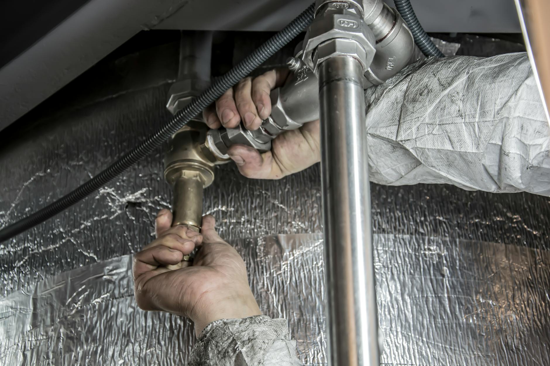 Ręce hydraulika montujące stalowe rury w instalacji wodnej w domu