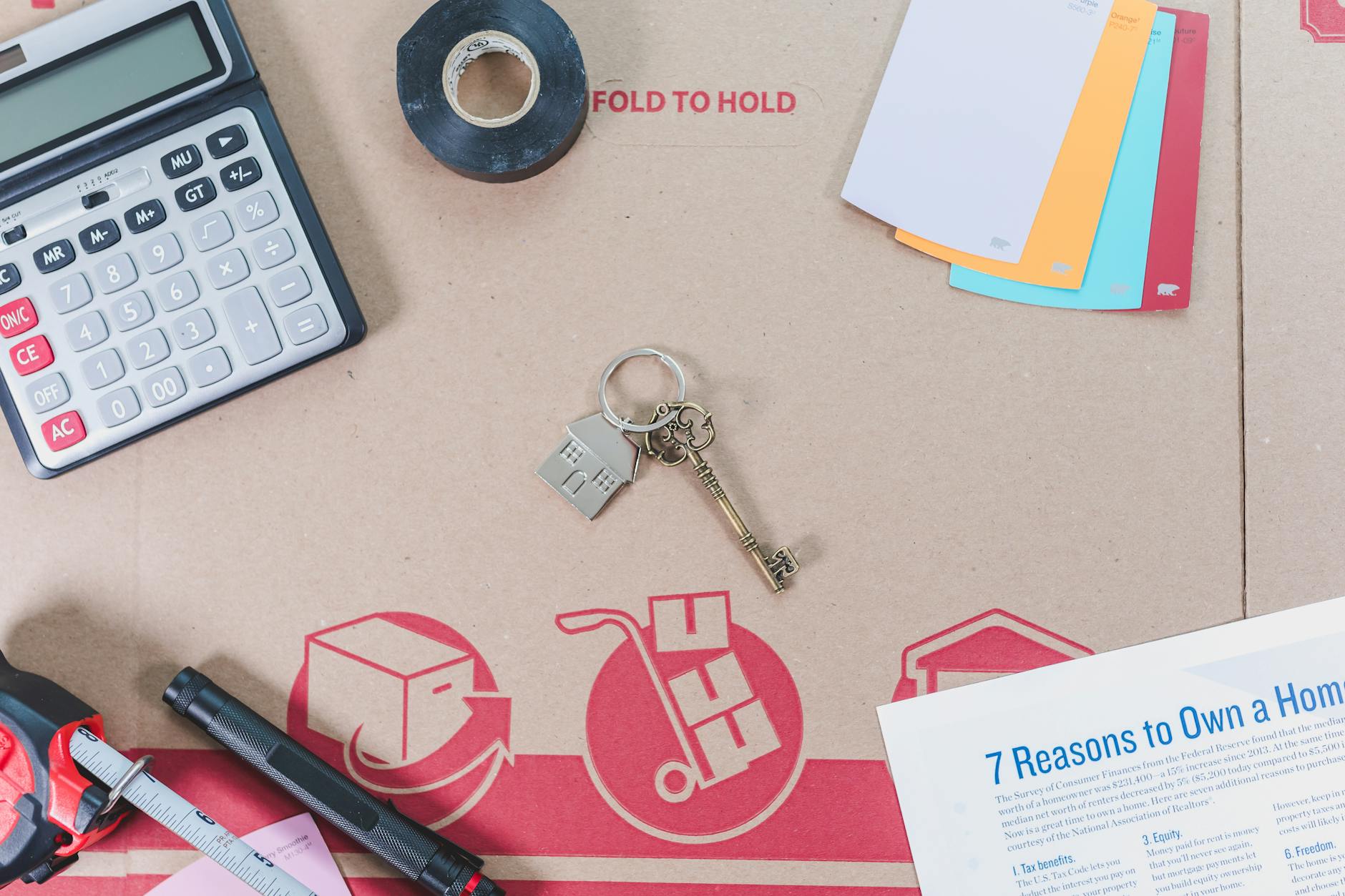 Kalkulator, klucze i miarka na stole przy planowaniu kosztów ocieplenia domu