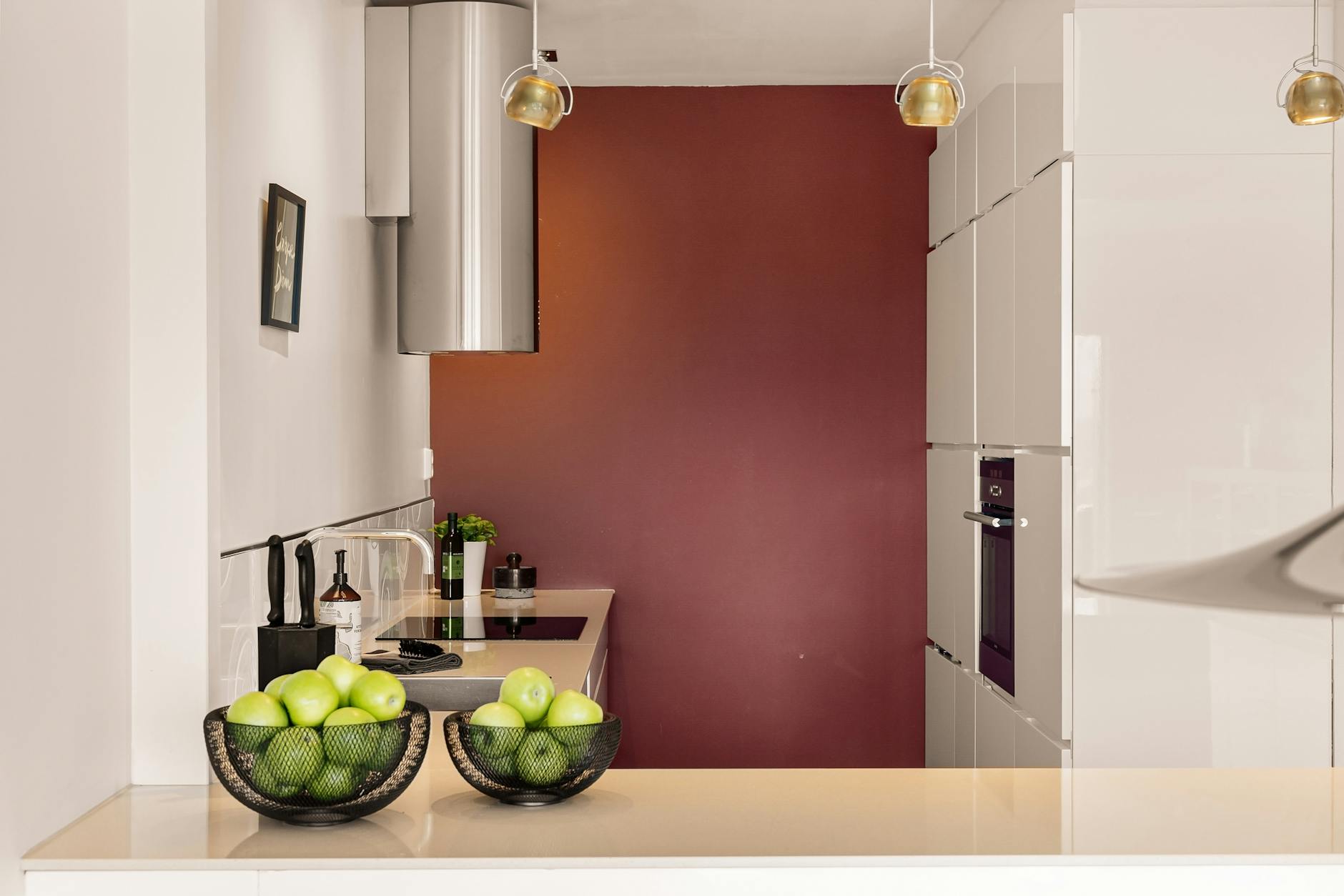 Nowoczesna kuchnia z białą zabudową i koszykiem zielonych jabłek