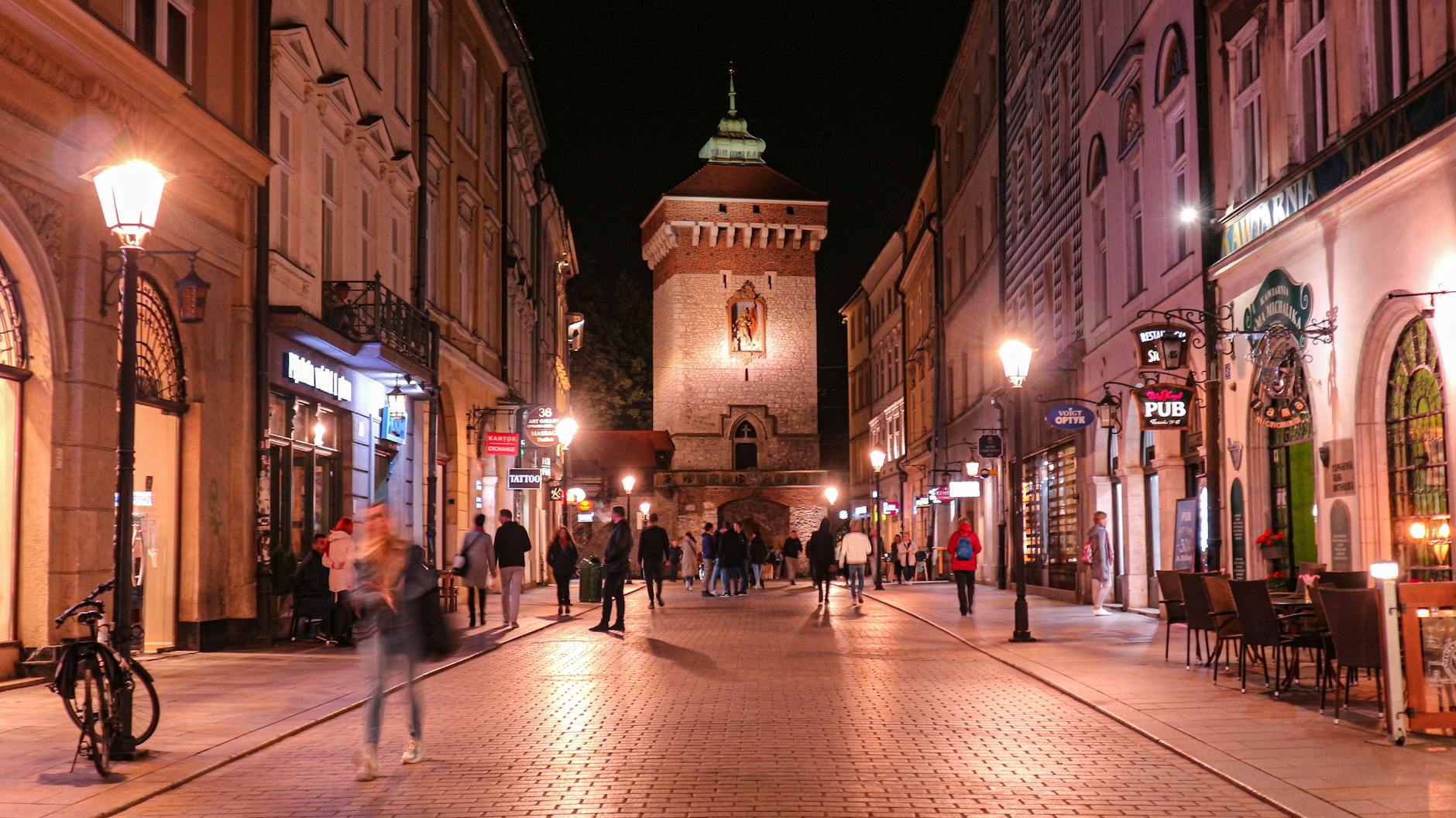 Brama Floriańska nocą w Krakowie, tłum spacerujących ludzi