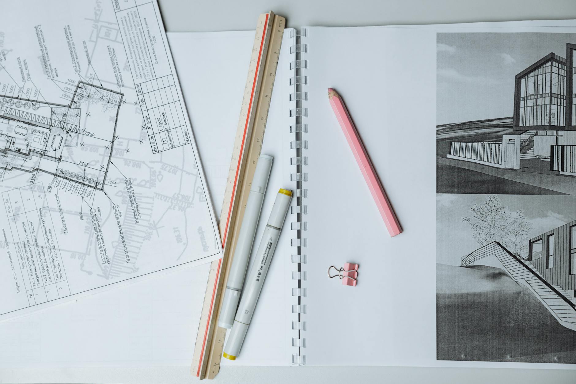 Plany architektoniczne z przyborami kreślarskimi rozłożone na biurku