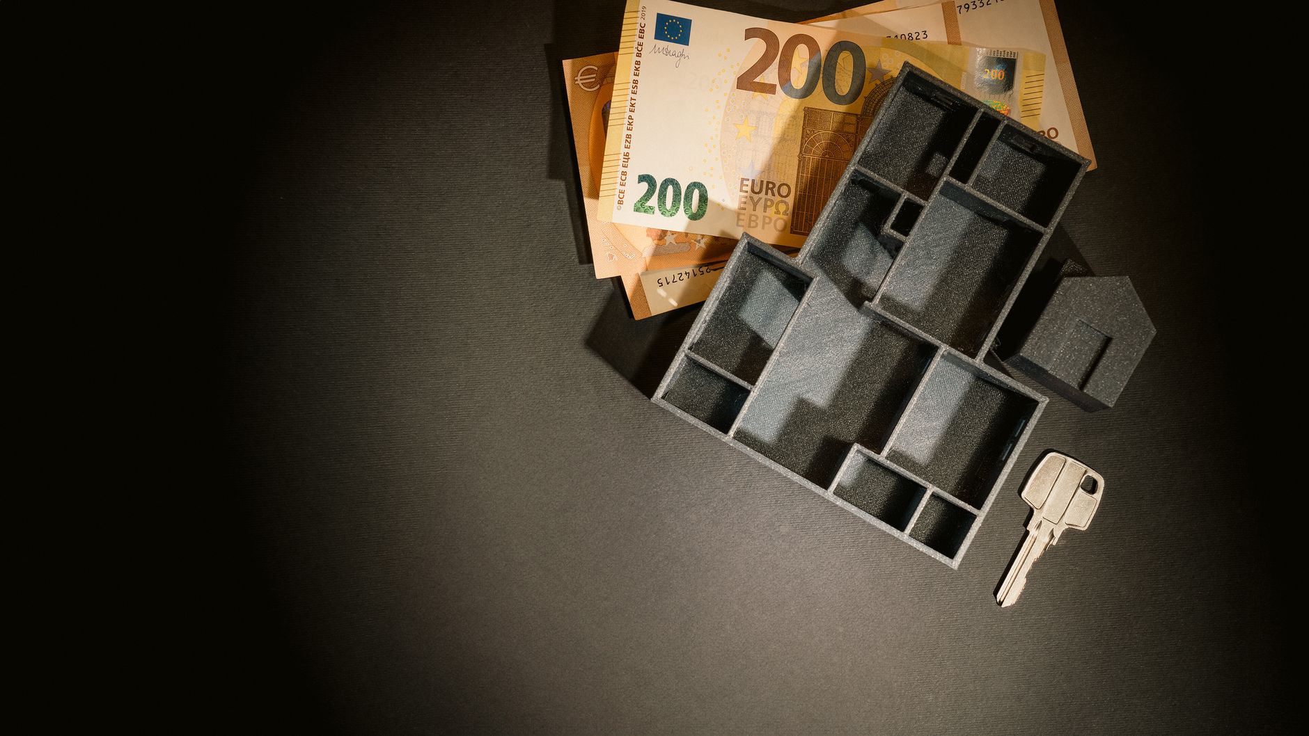 Banknoty euro, model domu i klucz na stole jako symbol finansowania budowy