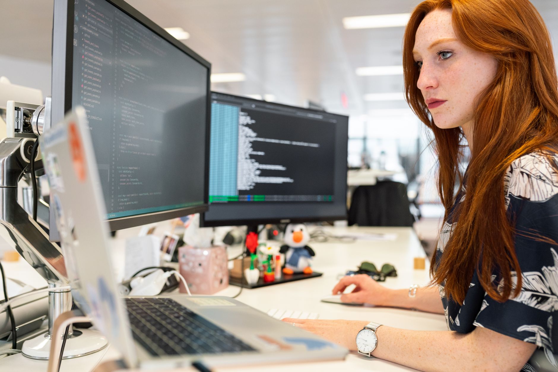 Programistka pracuje nad kodem DevOps przy dwóch monitorach w biurze